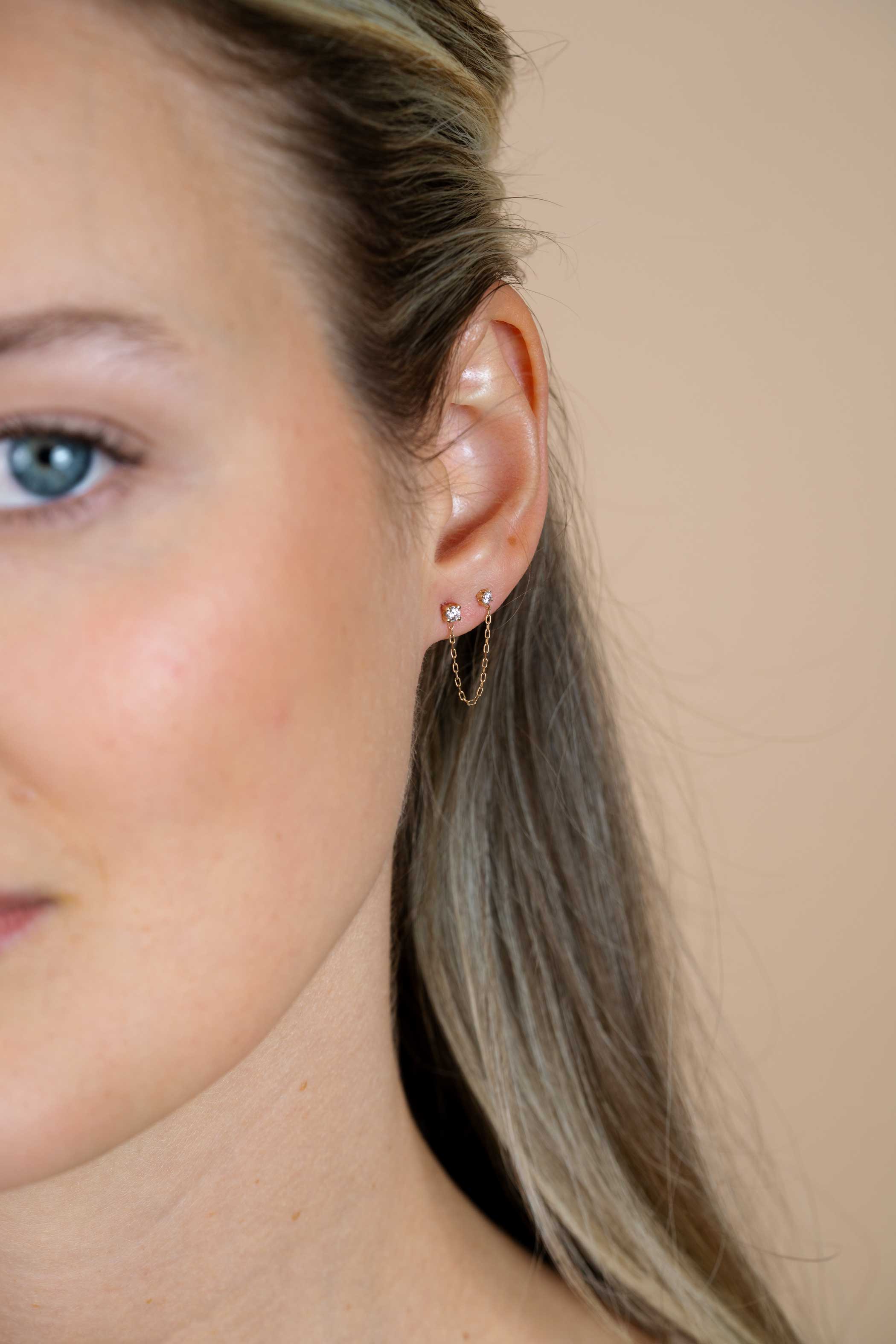 35mm ZINZI Gold 14 krt gouden dubbele oorstekers met verbonden ketting en witte zirkonia. Maar voor één oor. ZGO547 
